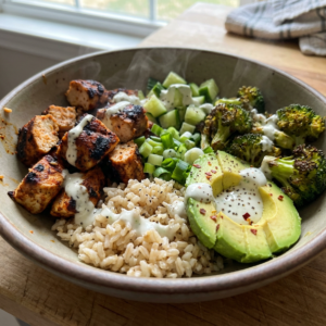Homemade 40g protein chicken power bowl with grilled chicken chunks, rice, roasted broccoli, avocado, cucumber, green onions, and creamy yogurt sauce. BuyMyRecipes.com